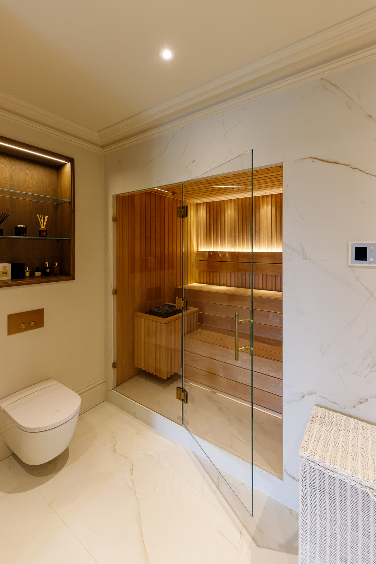 Large hinged sauna door with glass-to-glass antique brass hinges, ladder-style handle, Optiwhite glass and fixed panel in luxury bathroom