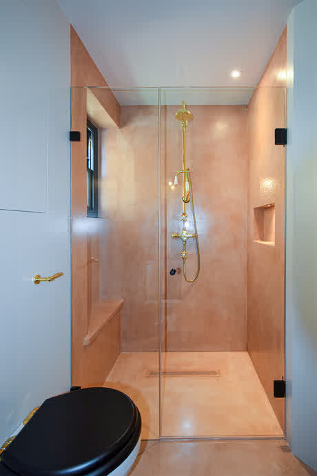 shower enclosure with dark bronze hinges and microcemented walls