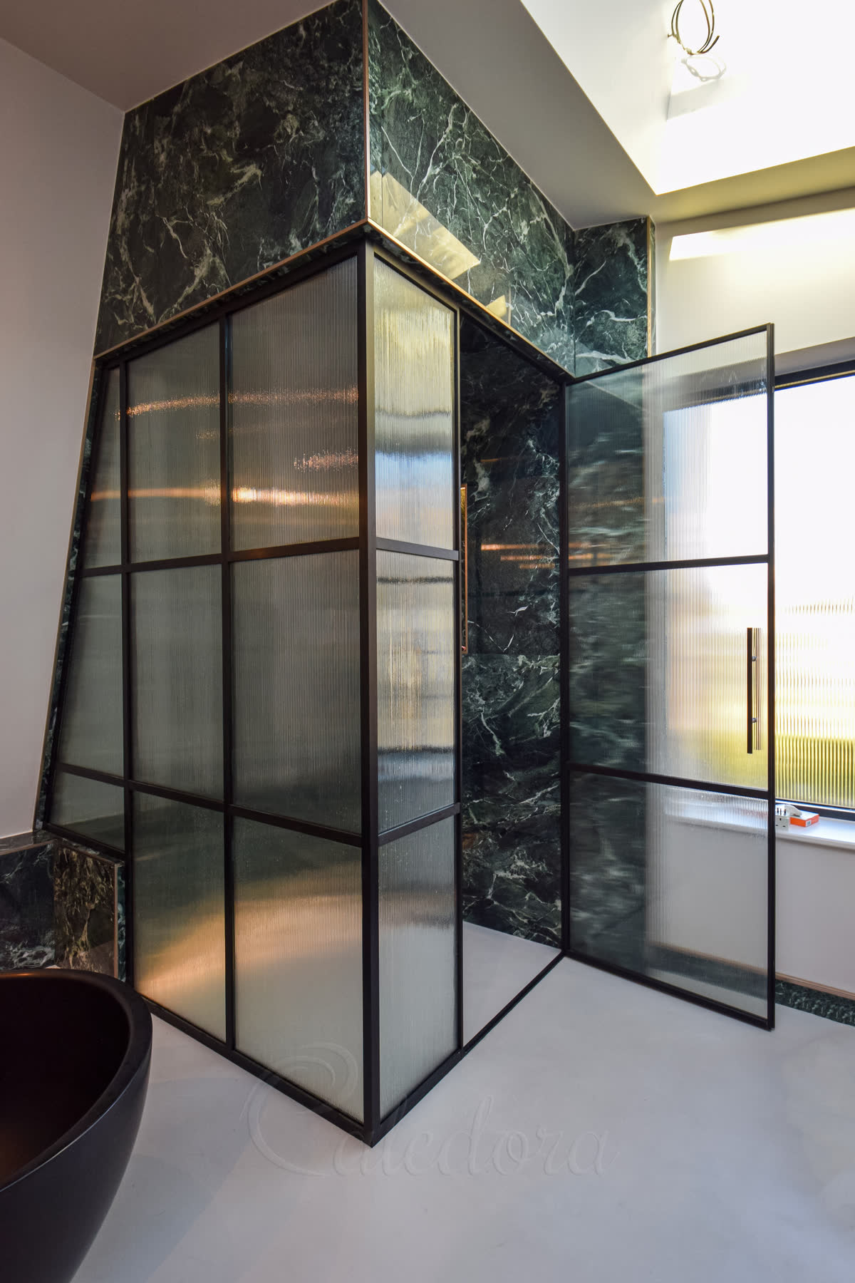 Black grid shower enclosure with fluted glass over bench, frame shaped to sloped ceiling, marble walls