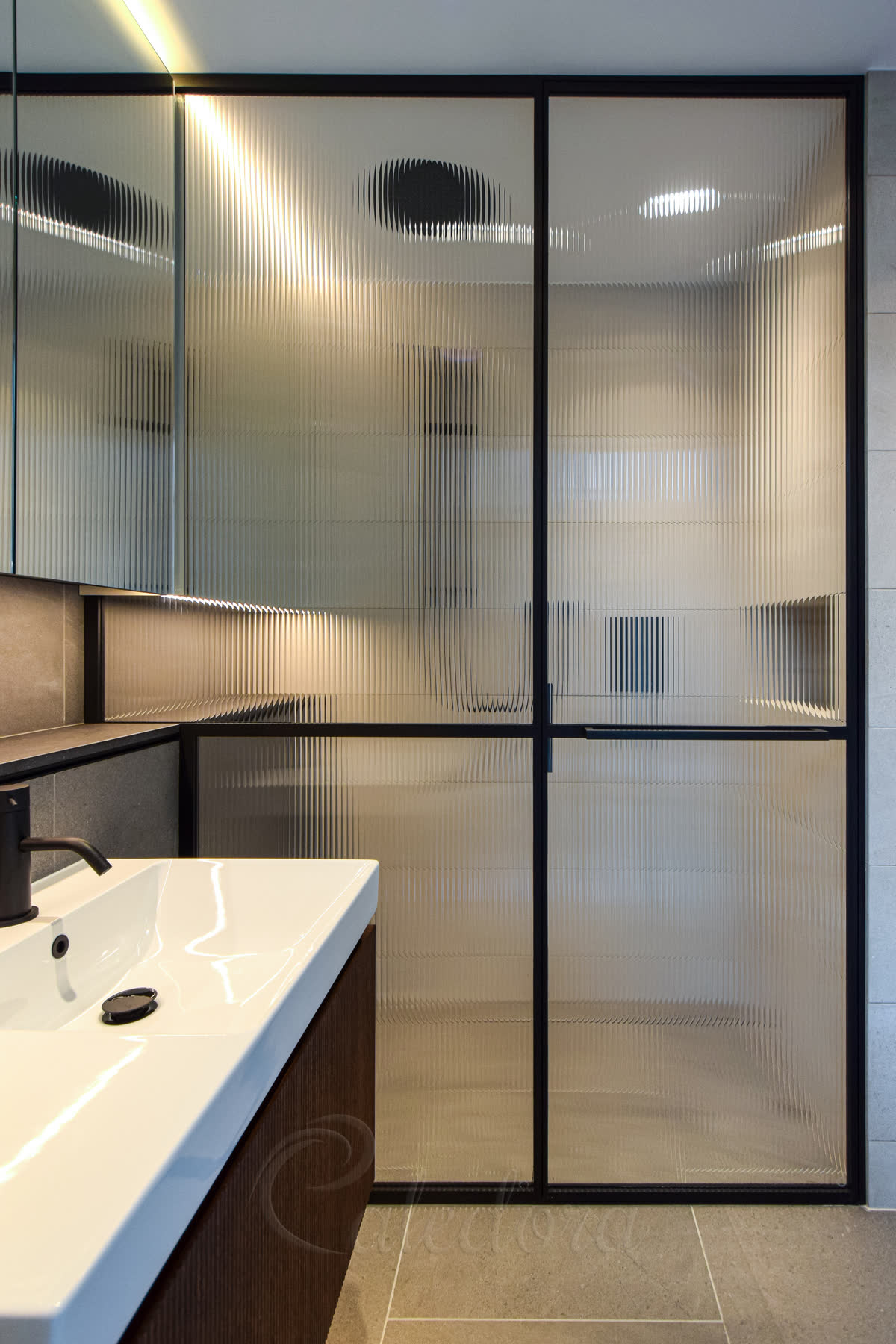 Inline shower enclosure with black frame and reeded glass panels