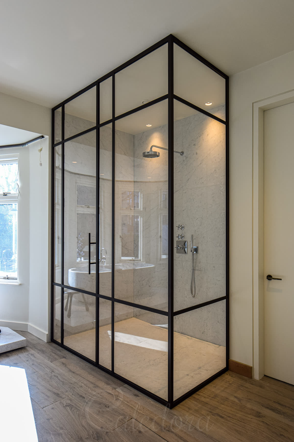 Large framed corner shower enclosure with satin bronze grid in luxury marble bathroom