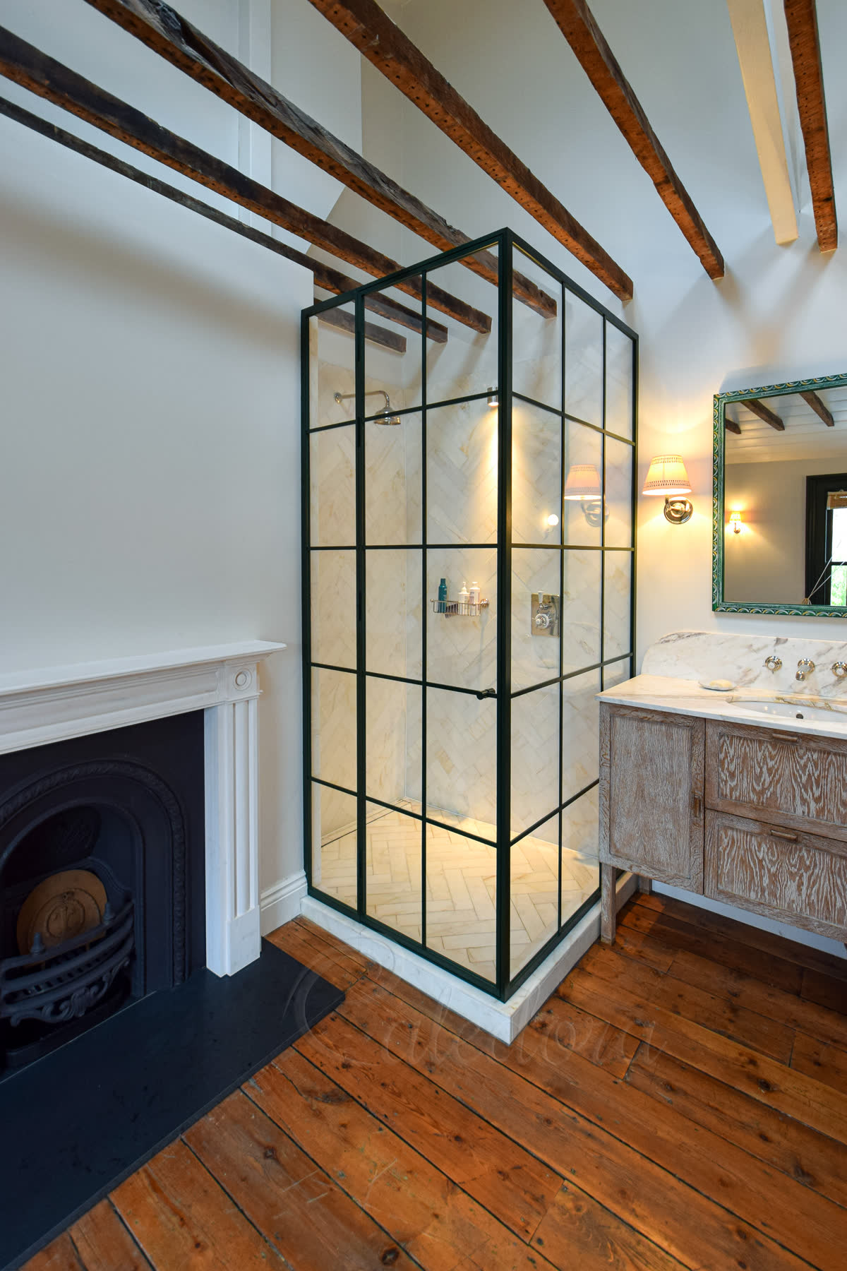 Dark green grid corner shower enclosure in period bathroom with exposed timber beams and fireplace