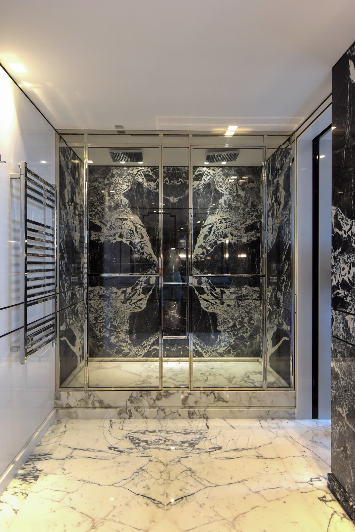 Inline shower enclosure with polished nickel frame, dual entry doors for two people, black marble walls