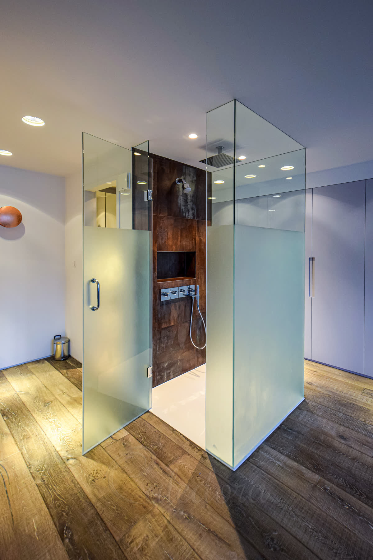 Three-sided frameless shower enclosure with partial frosted glass for privacy, chrome fixtures