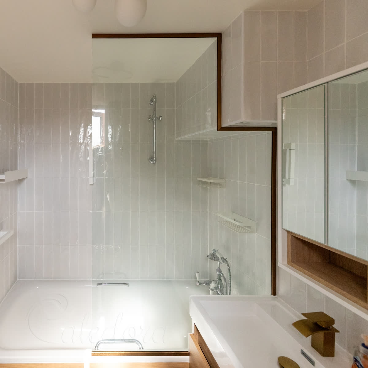 A fixed bath screen whose top steps down round a boxed-in beam, with a painted band along its edges matching the oak vanity unit beside the bath