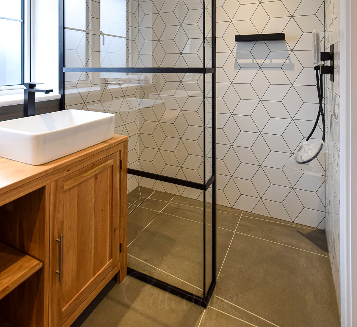 Black L-shaped walk-in shower screen with grid frame and UV-bonded fixed panels in a London bathroom