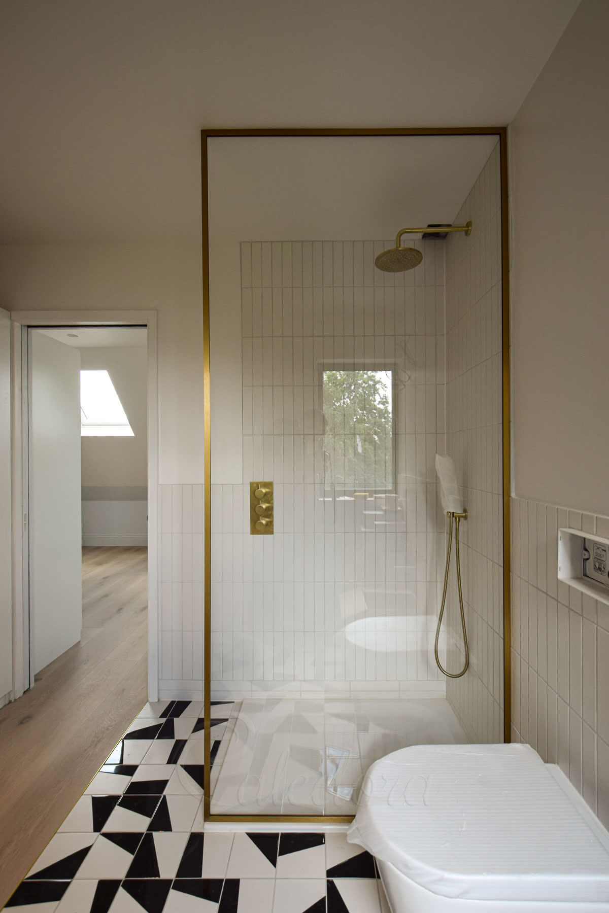 Fixed walk-in shower screen with satin brass perimeter frame, full height design, clear glass, white metro tiles, brass fixtures in contemporary bathroom