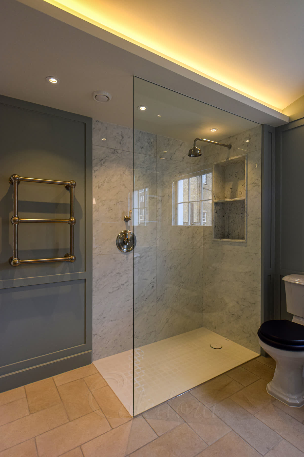 Frameless floor-to-ceiling shower screen recessed into a marble wall in a London bathroom