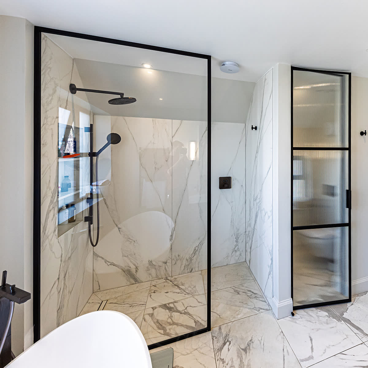 Matt black framed shower screen wall-fixed alongside a matching framed door in a London bathroom