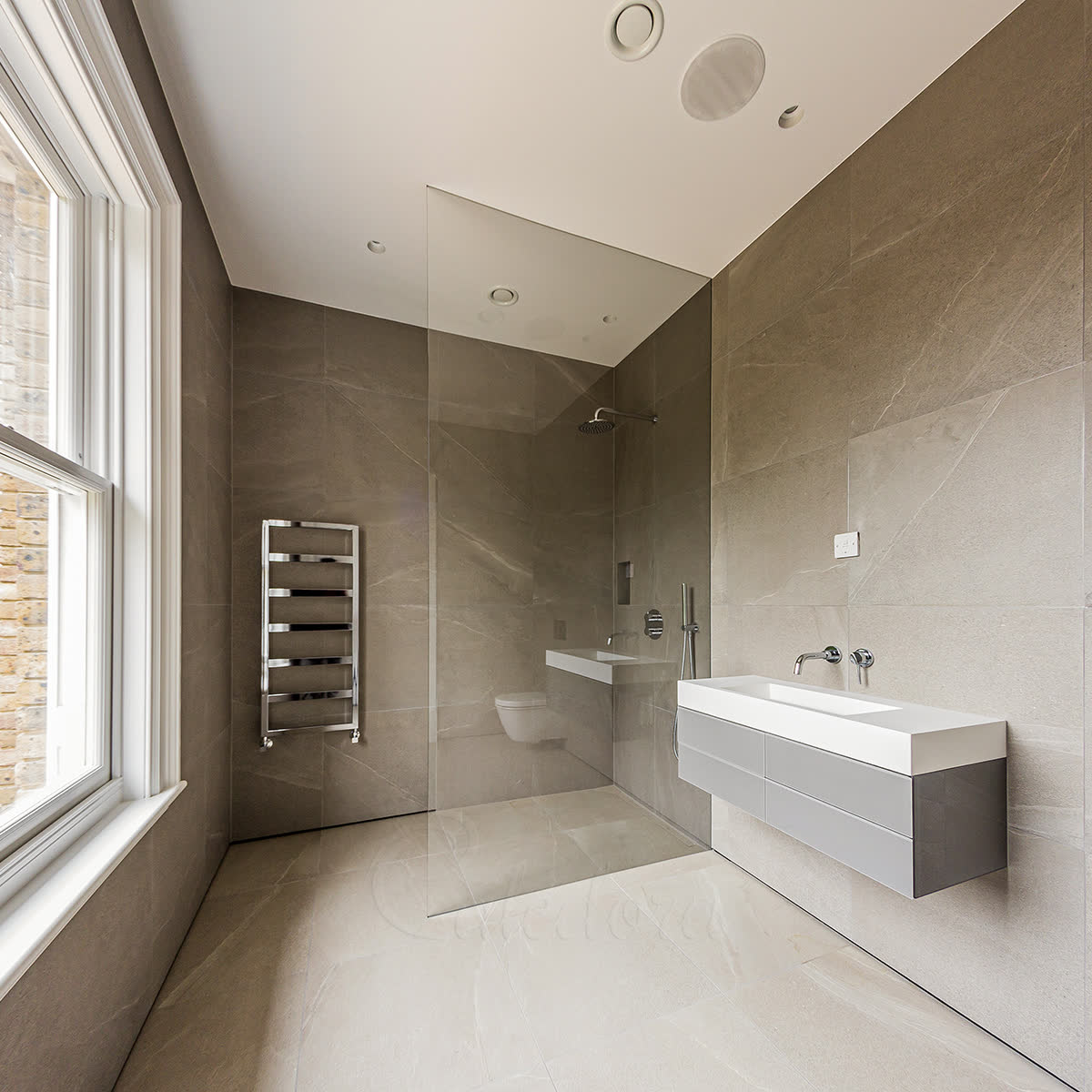 Frameless full-height shower screen recessed into the wall and running to the ceiling with no reinforcement bar in a London bathroom
