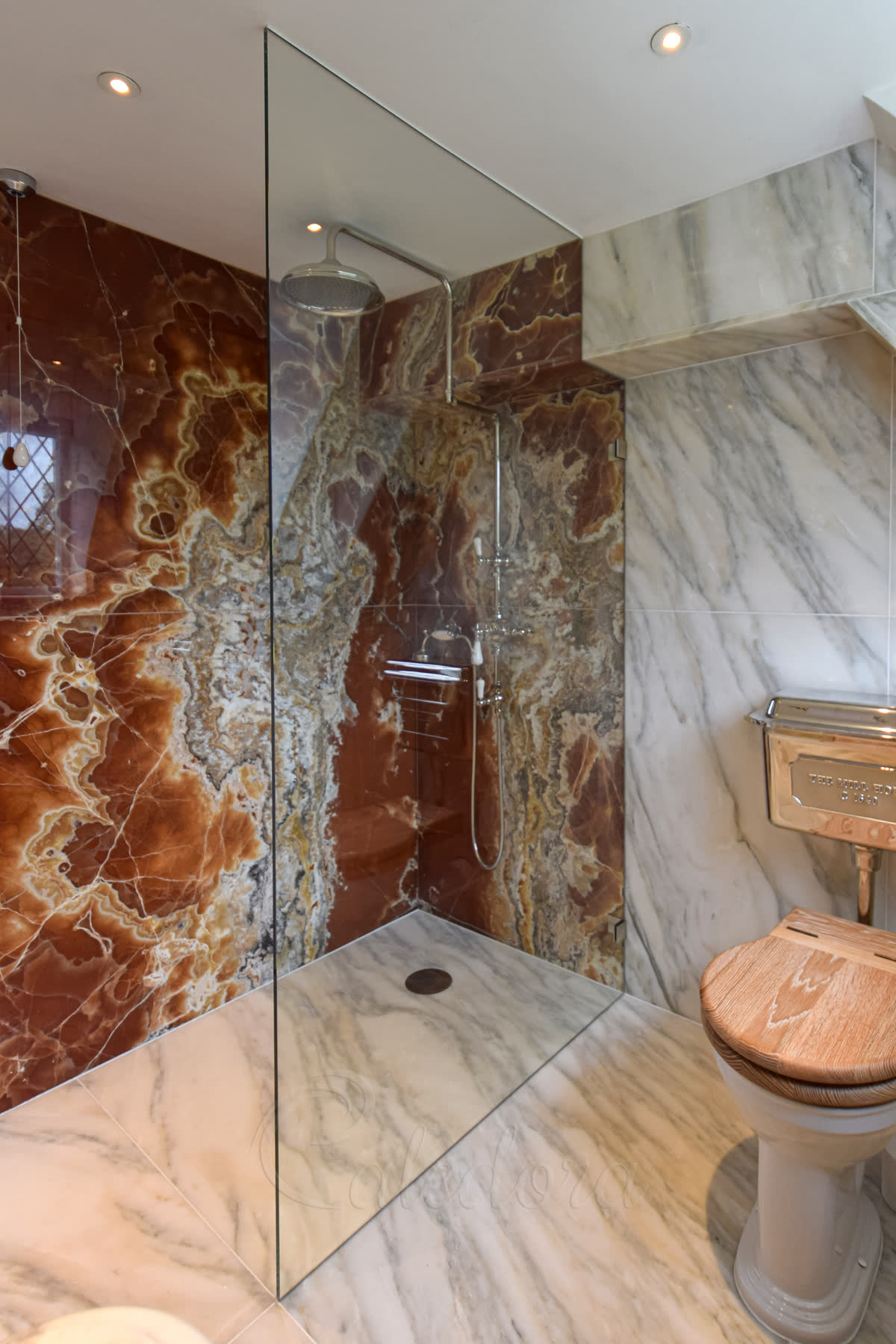 Custom glass shower panel with notched cut-out around tiled boxing, frameless full height walk-in design, luxury marble walls, bespoke installation