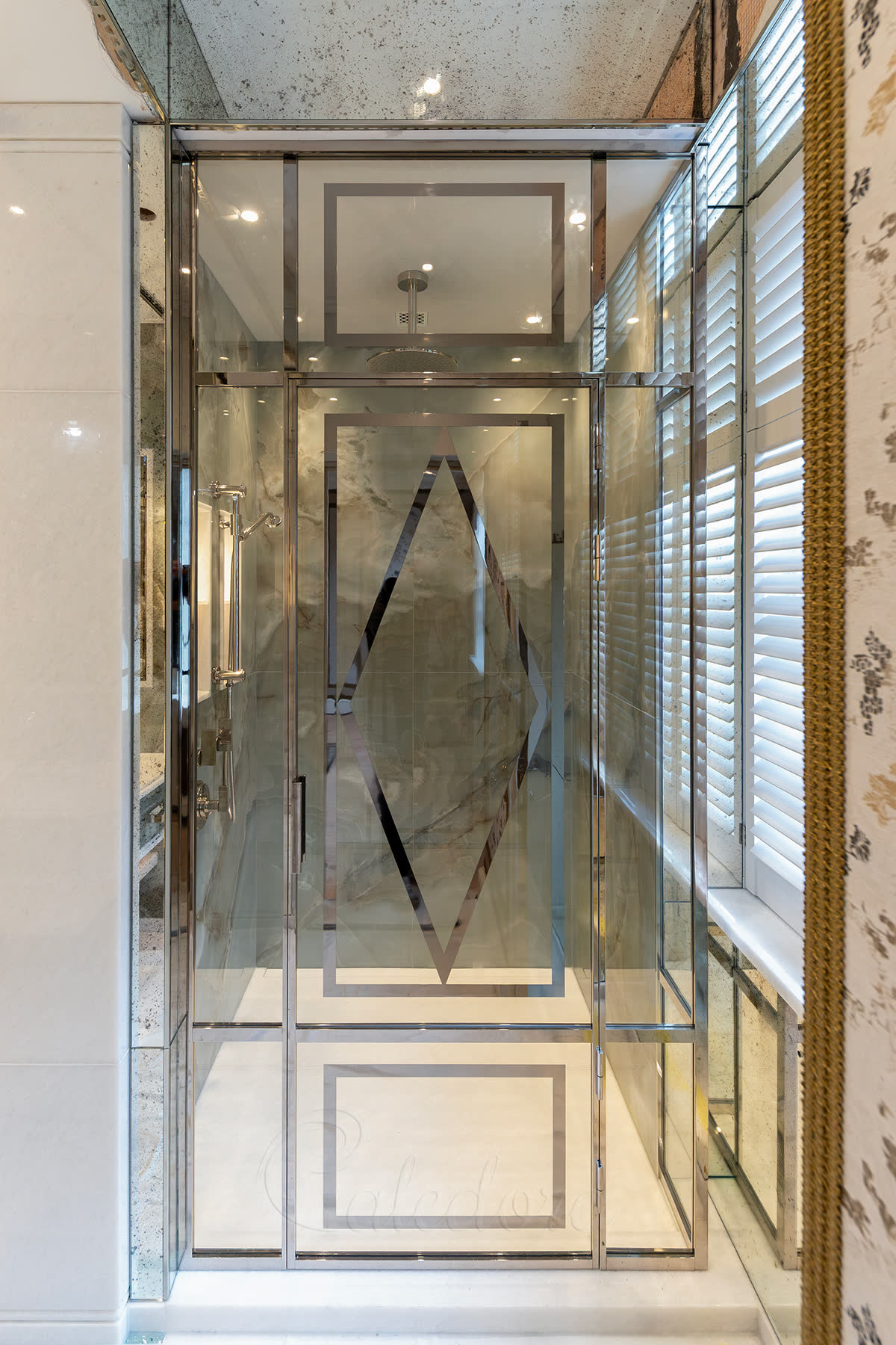 Bespoke shower enclosure with CNC-cut nickel-plated aluminium pattern laminated between two low-iron glass panels in a London bathroom