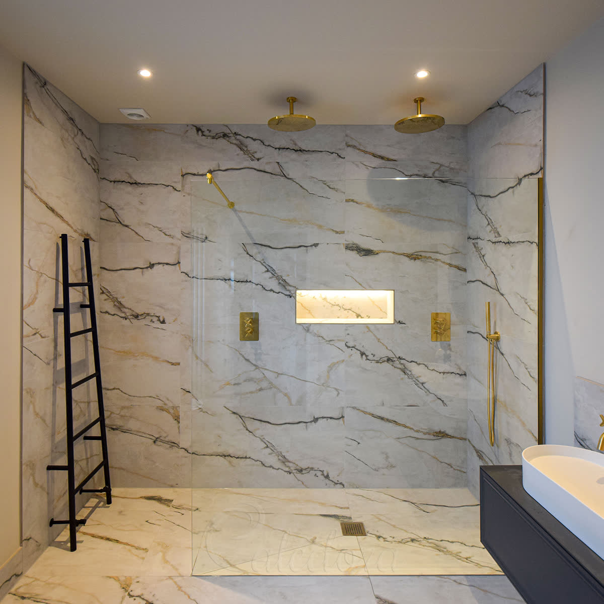 Large brushed brass walk-in shower screen with metal reinforcement bar fixed to the top edge in a Chelmsford bathroom