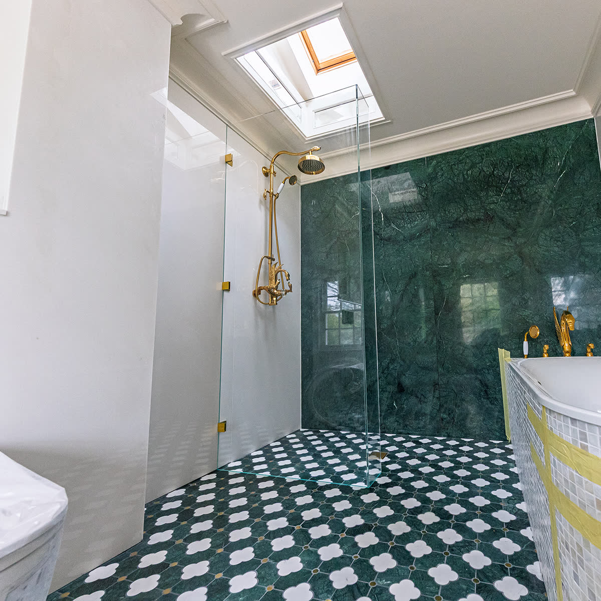 Frameless L-shape shower screen with return panel reinforcing the main glass at a corner in a London bathroom