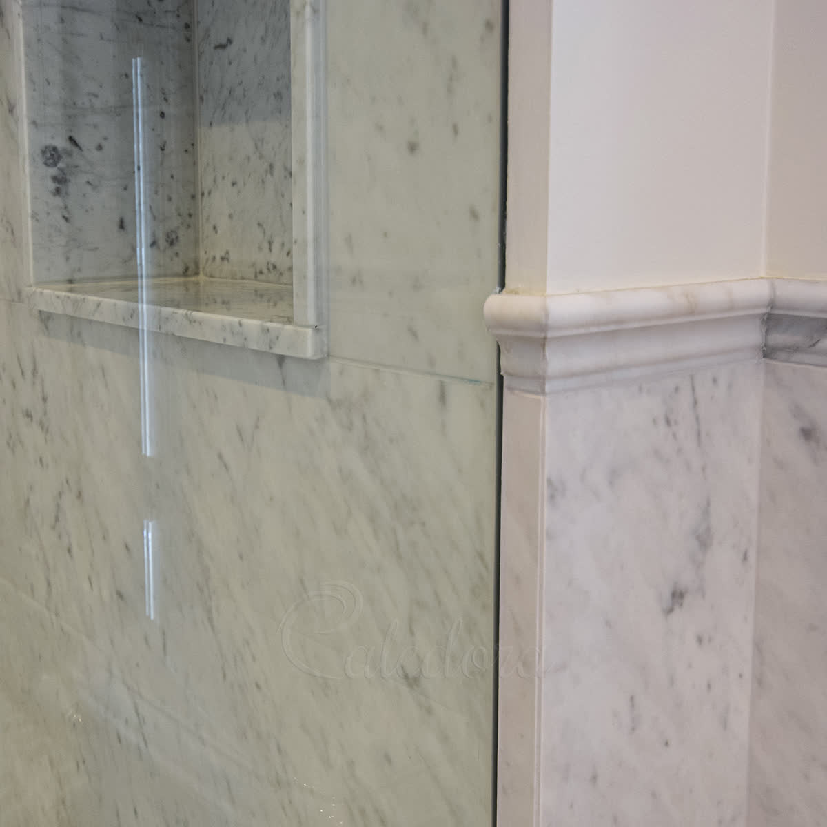Frameless full-height shower screen with the glass edge slotted directly into a groove cut in the tiled wall, no visible metal fixings
